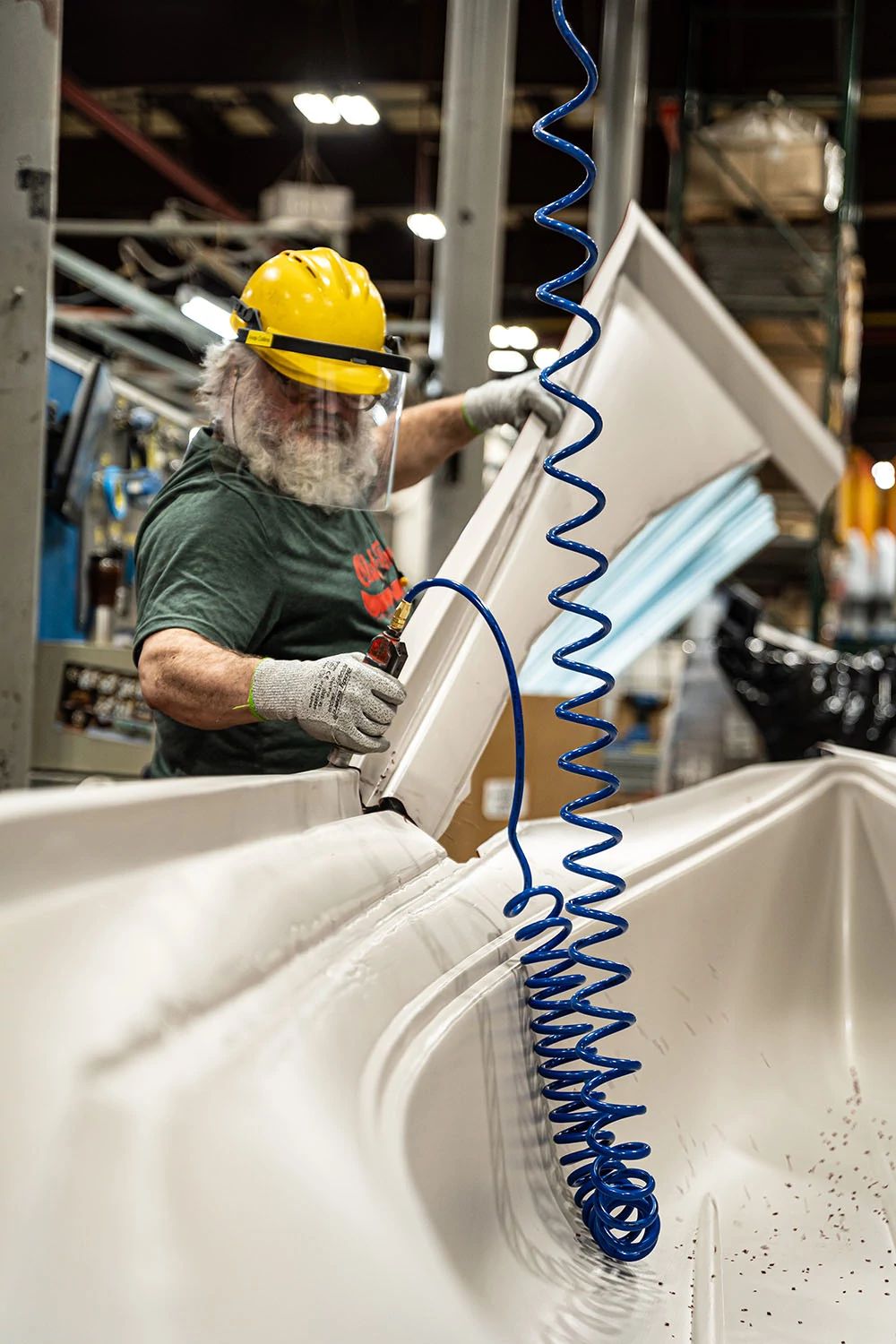 Man with air hose treating Old Town kayak in factory