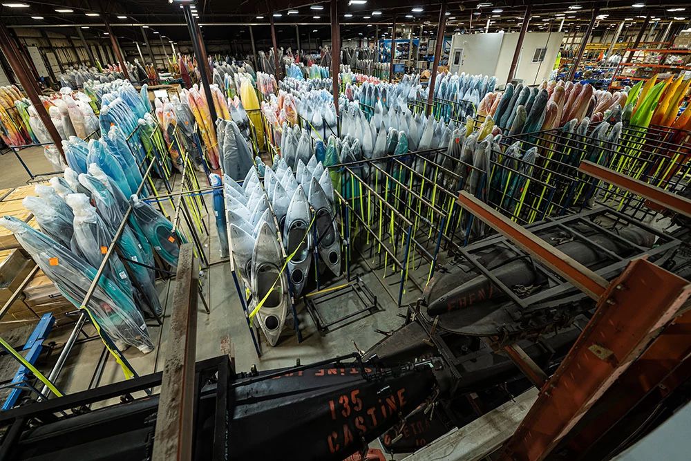 Kayaks standing upright in Old Town factory in plastic sheeting