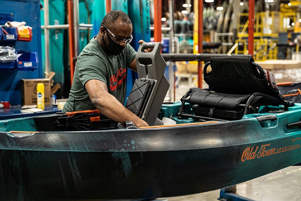 Man wearing mask assembling an Old Town kayak in factory