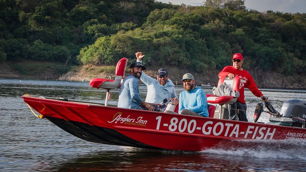 4 fishermen in bass fishing boat smiling as boat drives across lake